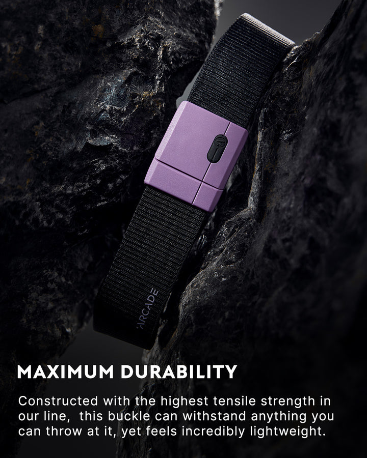A black fabric belt with a purple buckle is displayed draped over dark rocks. Text at the bottom highlights its maximum durability and lightweight design.