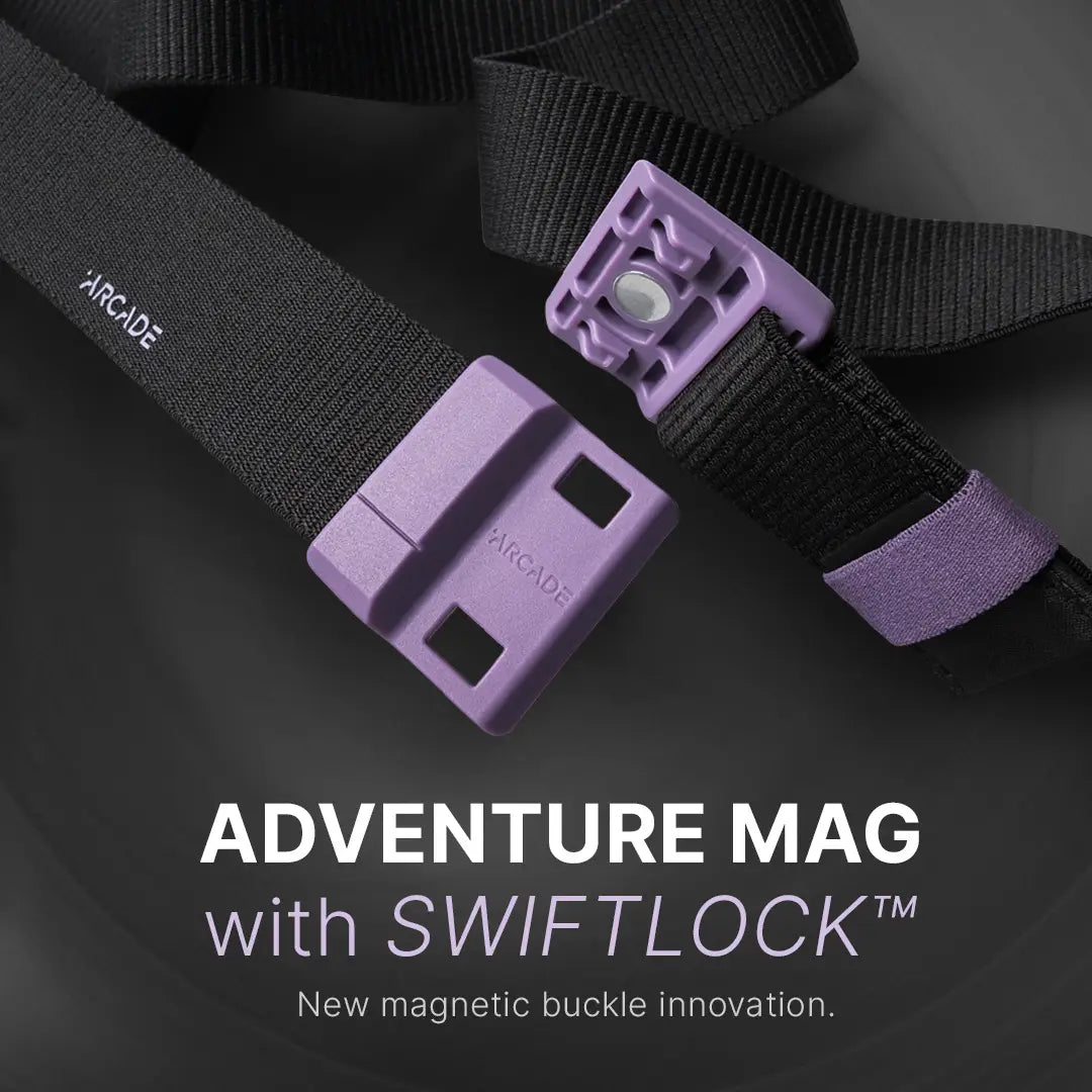 A close-up of a black belt with purple magnetic buckle parts, labeled Arcade. Text below reads: ADVENTURE MAG with SWIFTLOCK™. New magnetic buckle innovation.