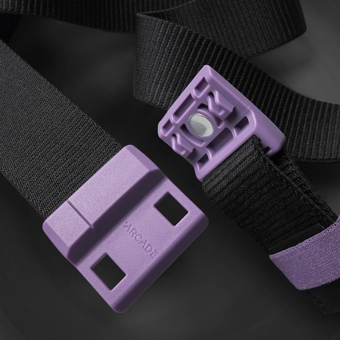 Close-up of a black fabric belt with a purple plastic buckle and fastener. The buckle is branded with the word ARCADE and both parts have a modern, geometric design.