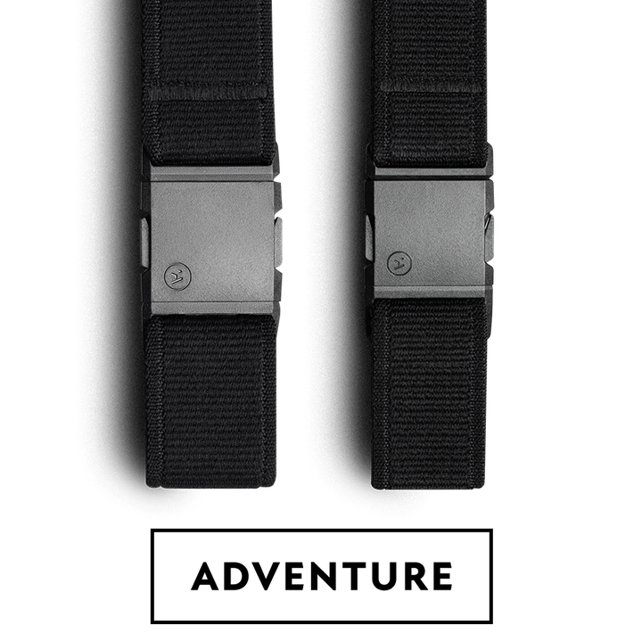 Two black nylon Arcade Belts with matte black rectangular buckles are shown side by side, each featuring a small circular logo on the buckle’s surface. The straps, perfect as travel belts, are oriented vertically against a white background.