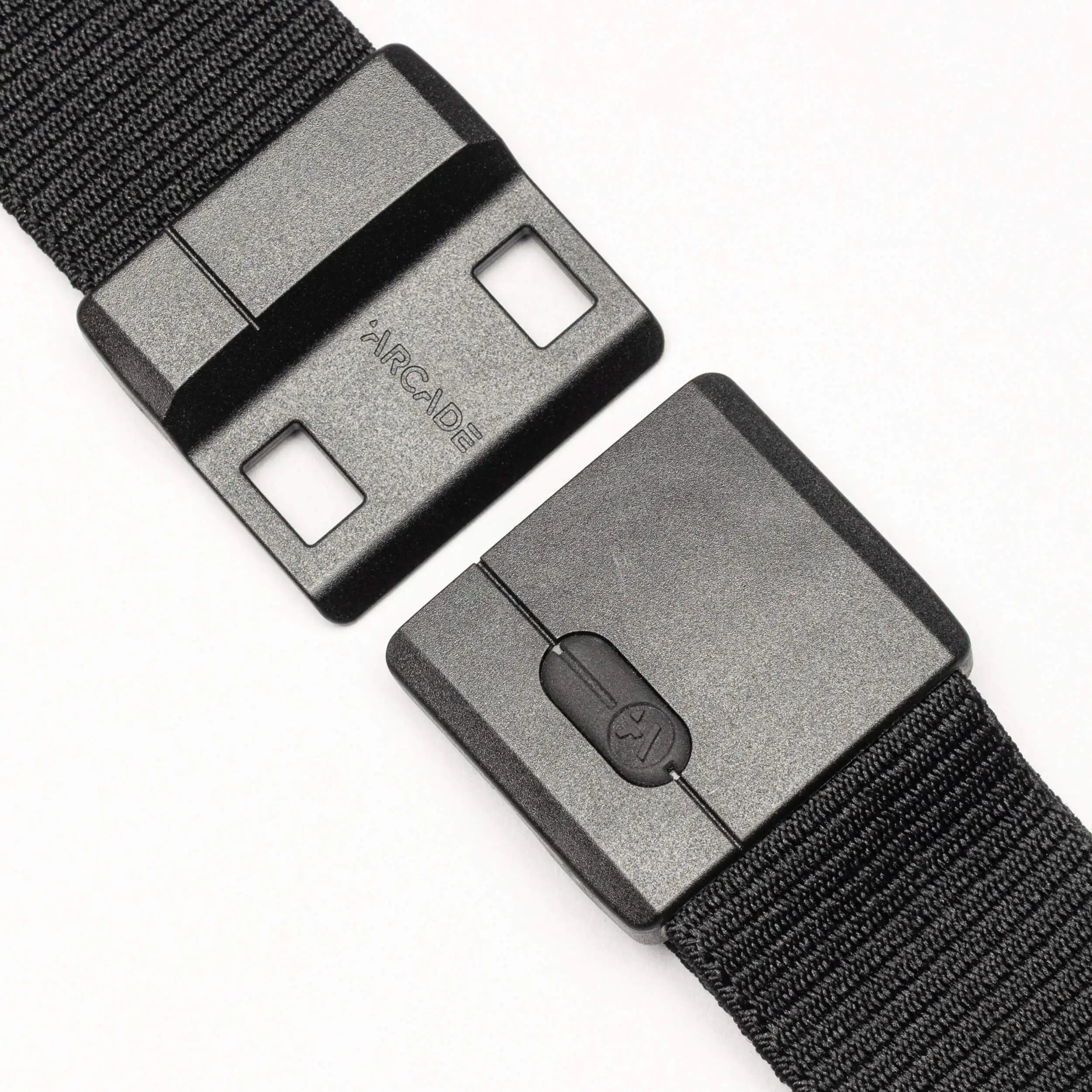 Close-up of the Aero belt by Arcade Belts—a black, durable belt with a rectangular plastic buckle featuring SwiftLock technology, two square holes, a button mechanism, and "ARCADE" text visible against a white background.