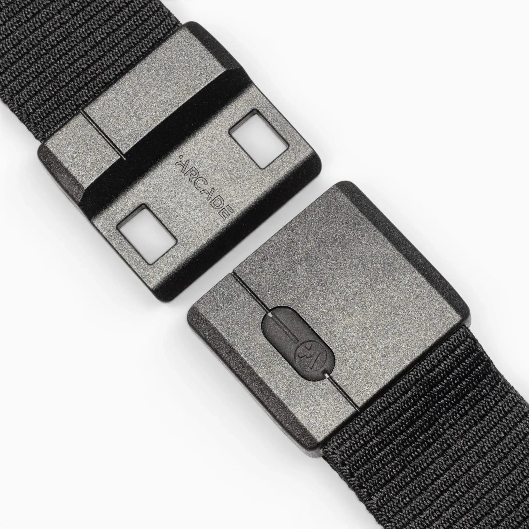 Close-up of the Arcade Belts Aero Mag: a black fabric belt with a rectangular grey plastic buckle, featuring two square holes and “ARCADE” embossed by the latch, designed with a durable buckle for long-lasting everyday wear.