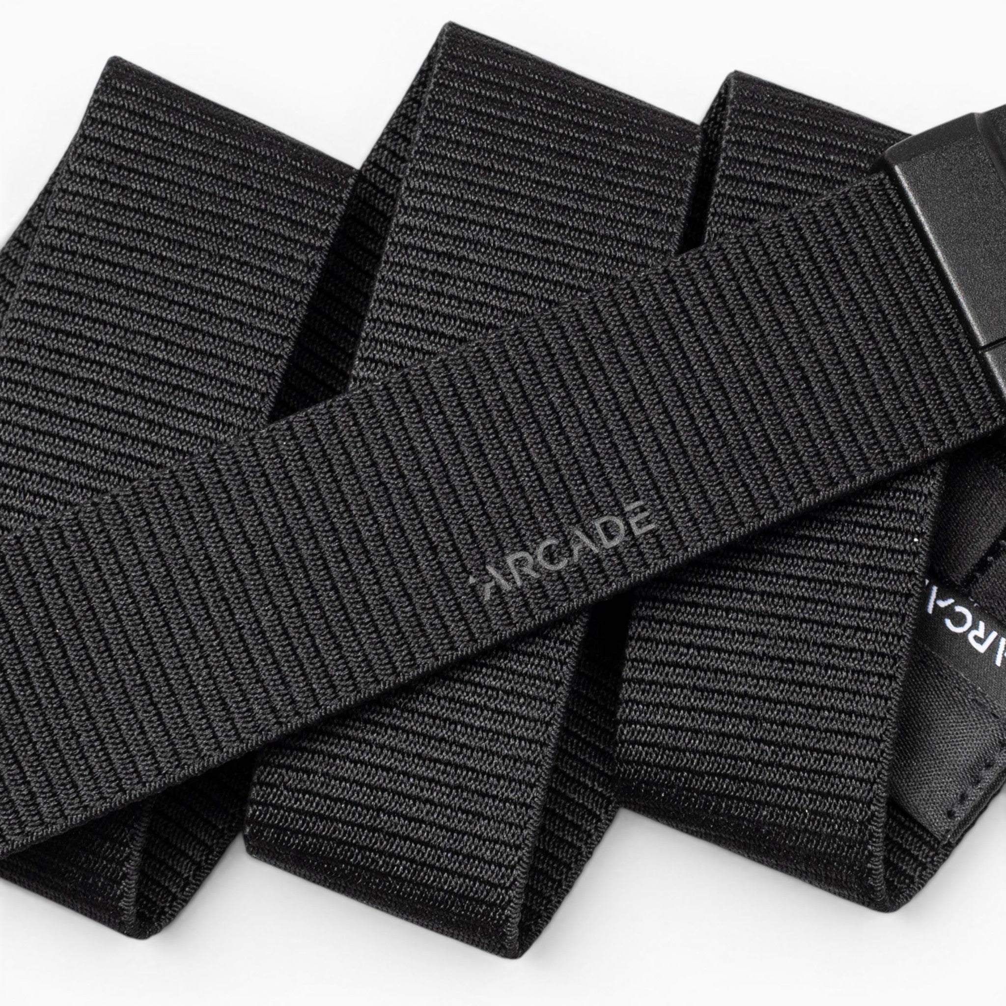 A close-up of the Aero Mag by Arcade Belts—a black, woven fabric belt with "Arcade" subtly printed on it—showcasing its textured material and an adjustable, durable buckle featuring a tension lock for secure fastening.