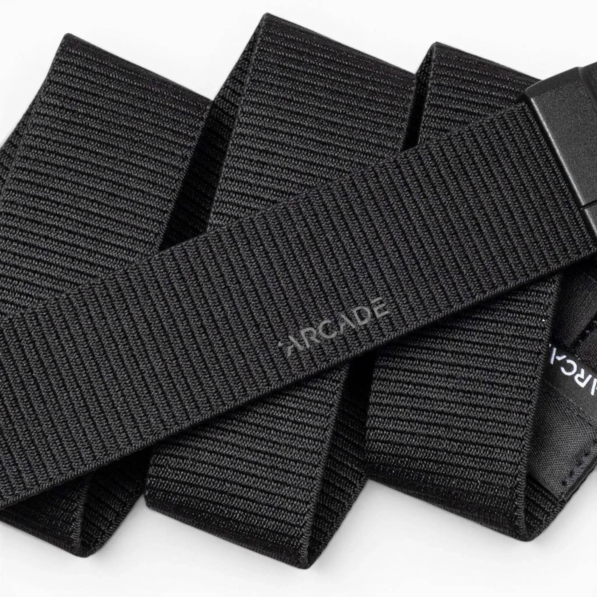 A close-up of the Aero Mag by Arcade Belts—a black, woven fabric belt with "Arcade" subtly printed on it—showcasing its textured material and an adjustable, durable buckle featuring a tension lock for secure fastening.