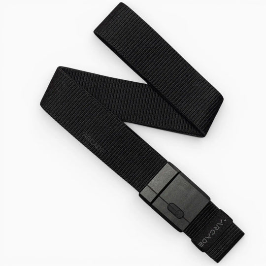 A black Mag Kit II woven nylon stretch belt by Arcade Belts, featuring a rectangular black plastic buckle, is displayed on a white background. The belt is partially folded, showcasing its flexible texture and modern minimalist design that exemplifies the adventurous spirit of Arcade Belts.