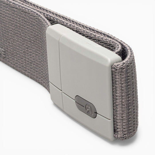 A close-up of the Arcade Belts Aero Mag, a gray fabric belt featuring a rectangular, light gray plastic buckle with a small metallic detail and a notched pattern that highlights its durable design. The background is white.