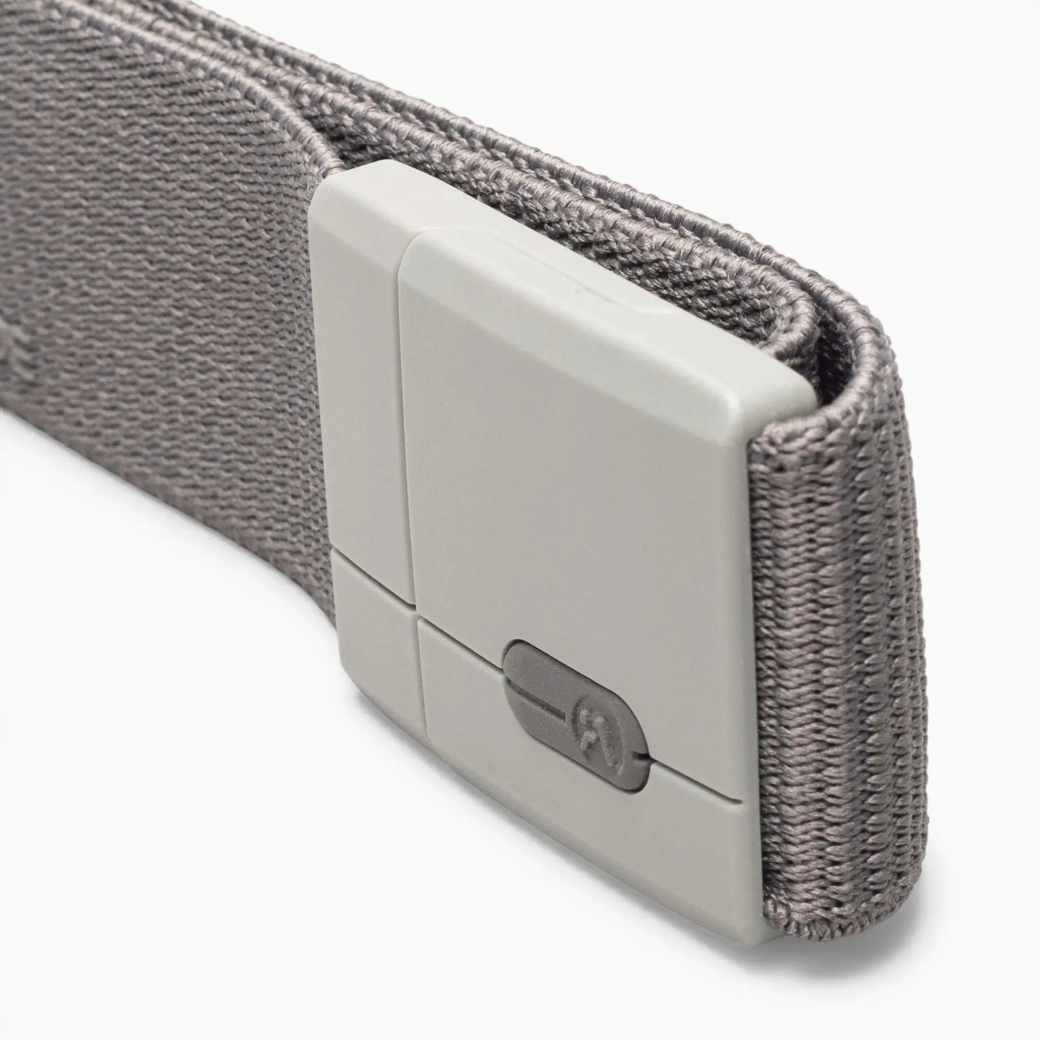 A close-up of the Arcade Belts Aero Mag, a gray fabric belt featuring a rectangular, light gray plastic buckle with a small metallic detail and a notched pattern that highlights its durable design. The background is white.