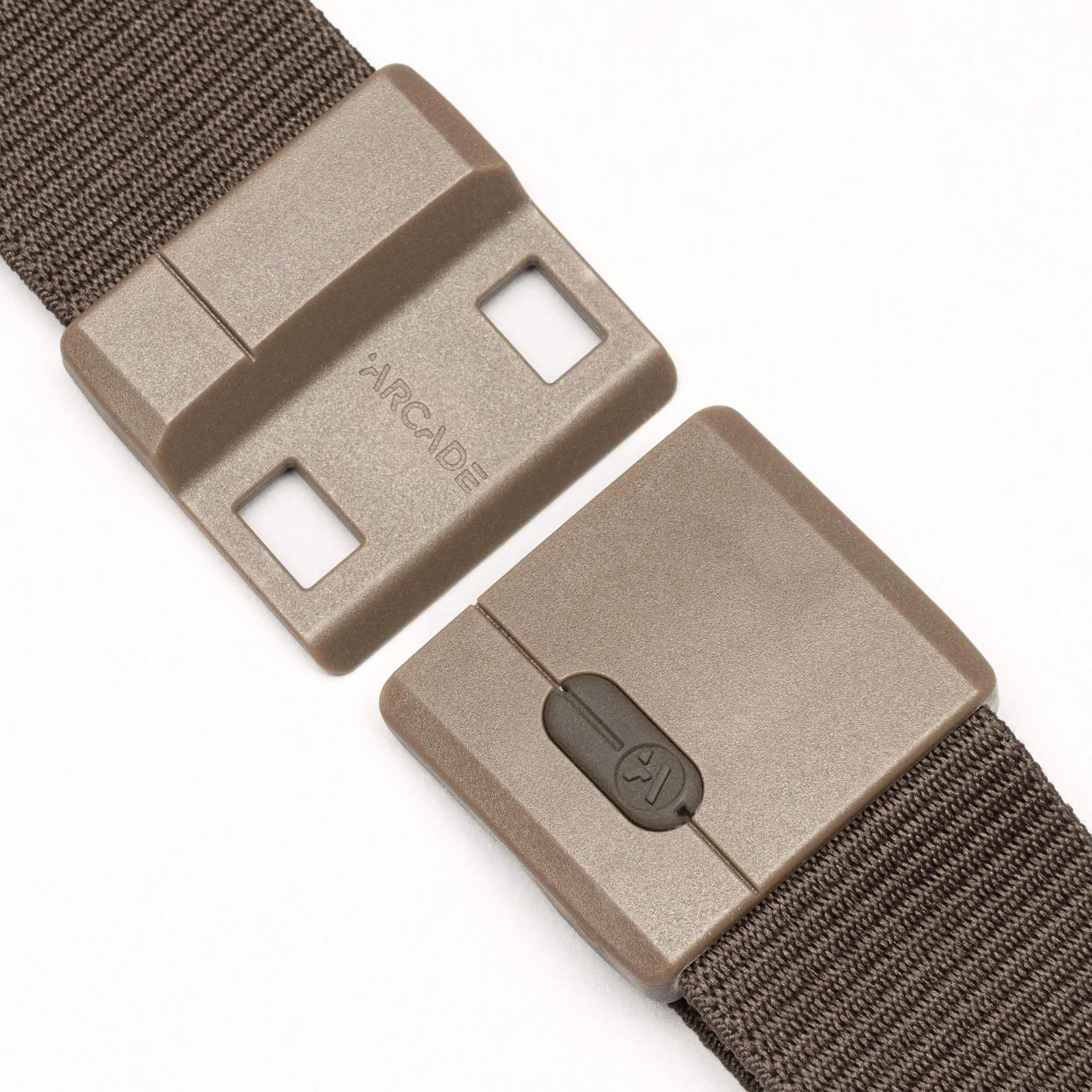 A close-up of the brown Aero nylon belt by Arcade Belts, featuring a sturdy rectangular plastic buckle with two interlocking pieces—one with slots and the other with a push-button release. "Arcade" is embossed on one side of the buckle.