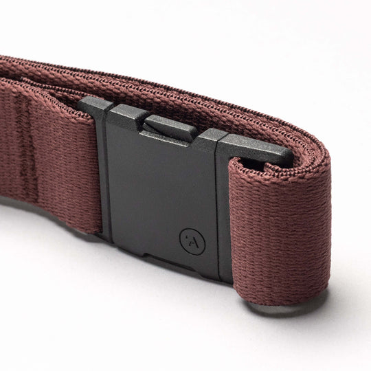 A close-up of an Arcade Belt Co. strap by Arcade Belts, featuring brown fabric and a black rectangular plastic buckle, photographed against a plain white background.