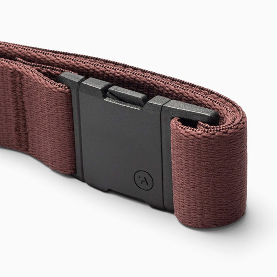 A close-up of the Arcade Belt Co. by Arcade Belts, featuring a maroon fabric design with a black rectangular buckle and displayed on a white background, highlights the subtle pops of color and showcases this performance stretch belt for added comfort.