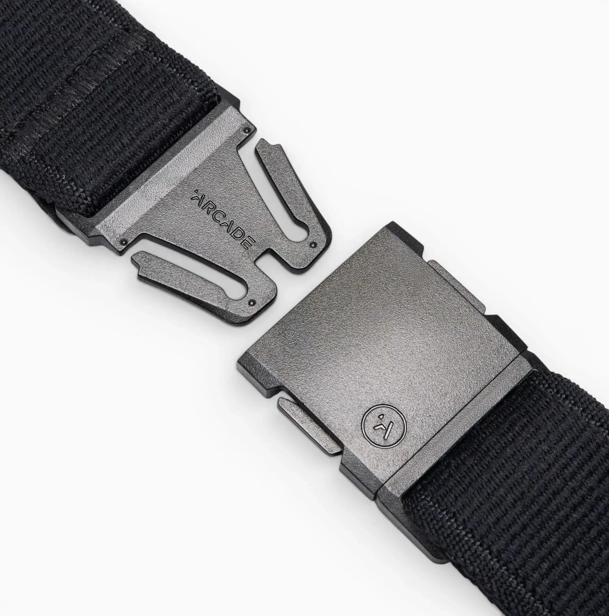 Close-up of the Arcade Belts Midnight Long Kit elastic stretch belt with a metal buckle, showing both separated ends. One end features the brand name Arcade, and the other has a small circular logo against a white background.