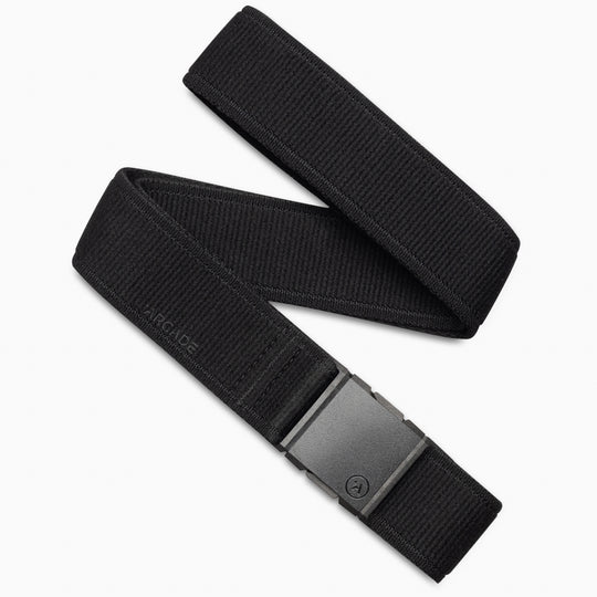 The Atlas Kit by Arcade Belts is a black stretch webbing belt with a matte black rectangular buckle, shown coiled on a white background. ARCADE is subtly embossed near the buckle—ideal for those seeking stylish travel belts.