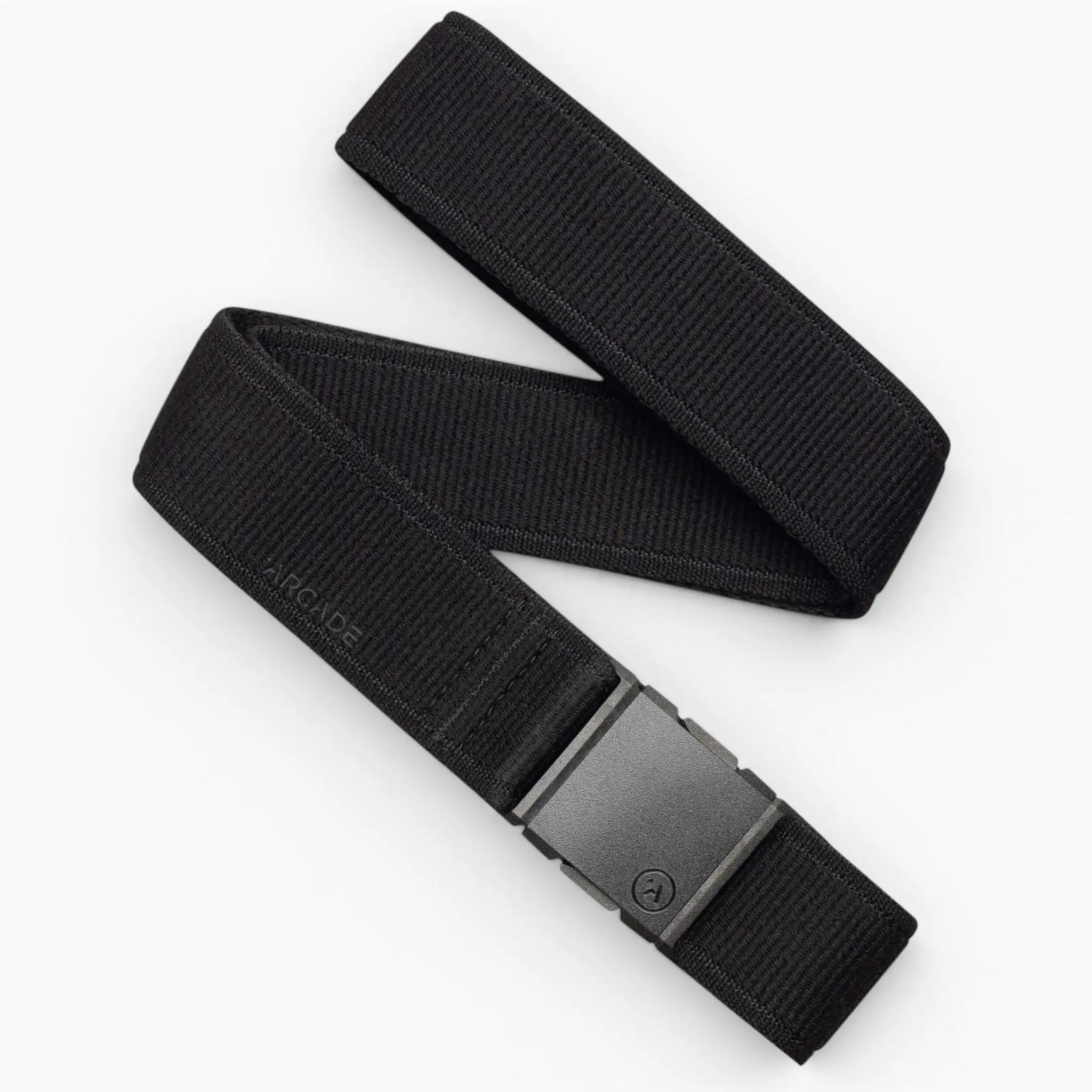 A black fabric belt from Arcade Belts is displayed on a white background, featuring a subtle ARCADE logo near the rectangular black buckle. Inspired by the Atlas Gifting Kit, this accessory boasts a signature performance stretch design for all-day comfort and showcases the innovative A2 buckle system for enhanced security and style.