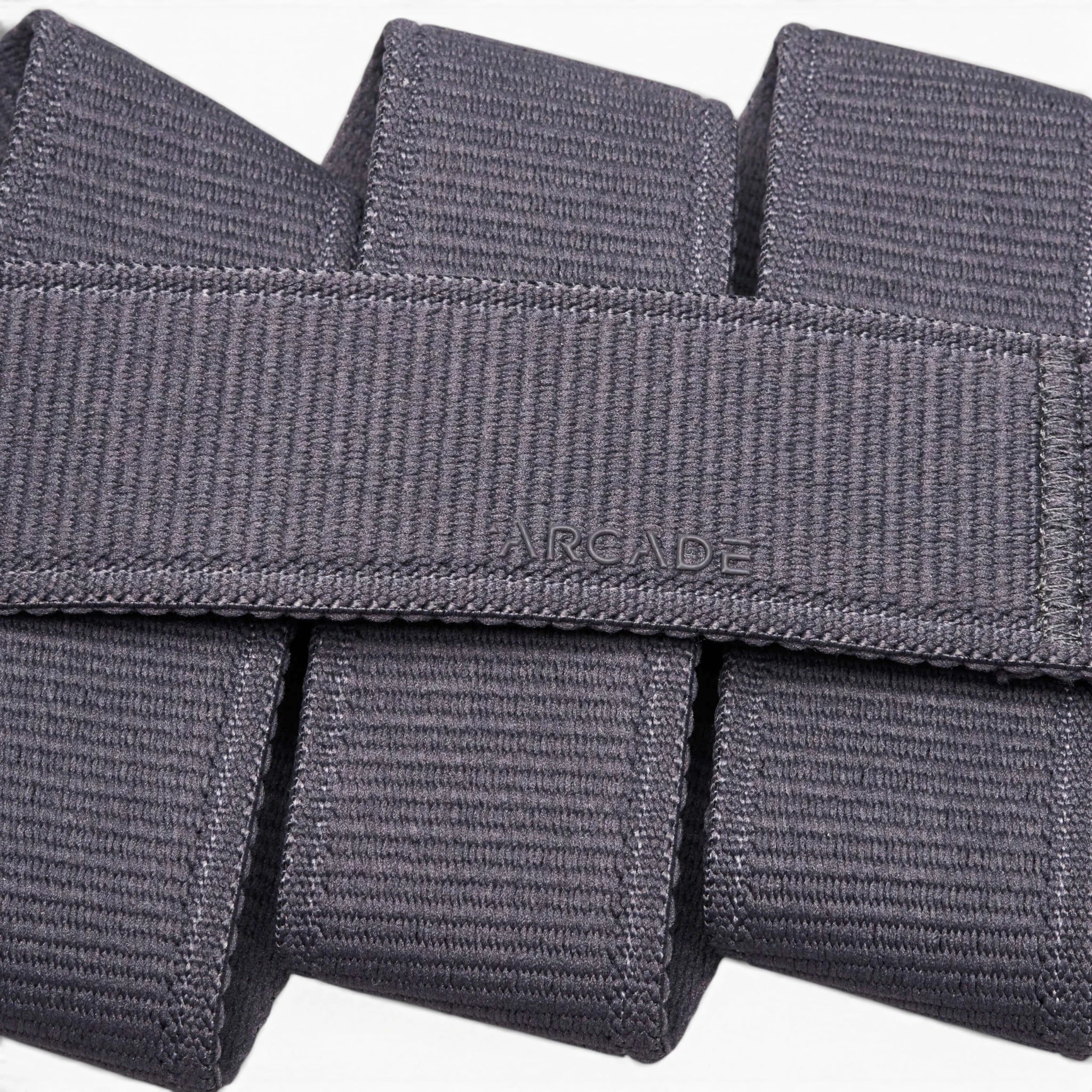 Close-up of the Atlas belt by Arcade Belts, crafted in grey stretch webbing. The word ARCADE is stitched at the center, showcasing its signature woven texture and neatly folded design.