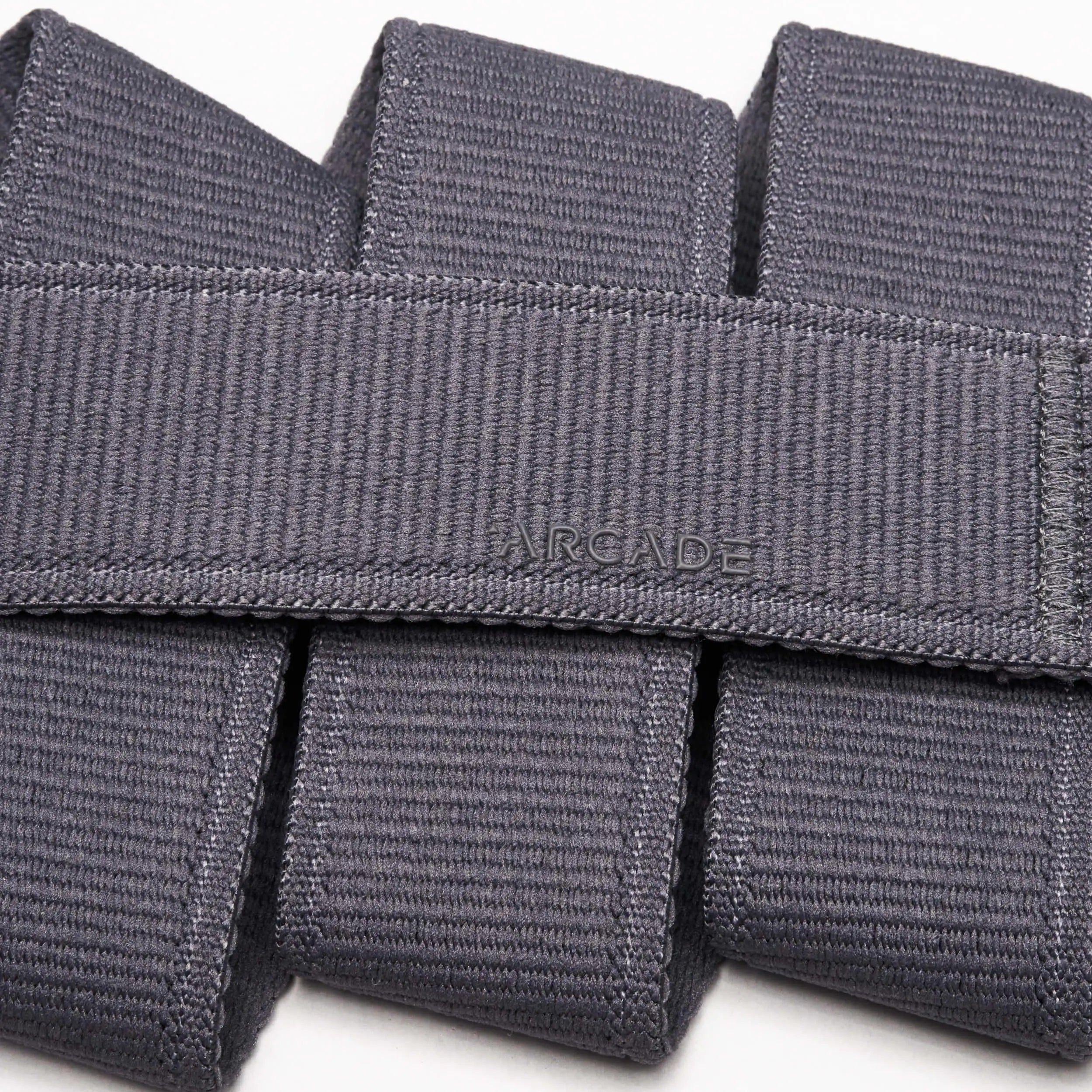 Close-up of the Atlas belt by Arcade Belts, crafted in grey stretch webbing. The word ARCADE is stitched at the center, showcasing its signature woven texture and neatly folded design.