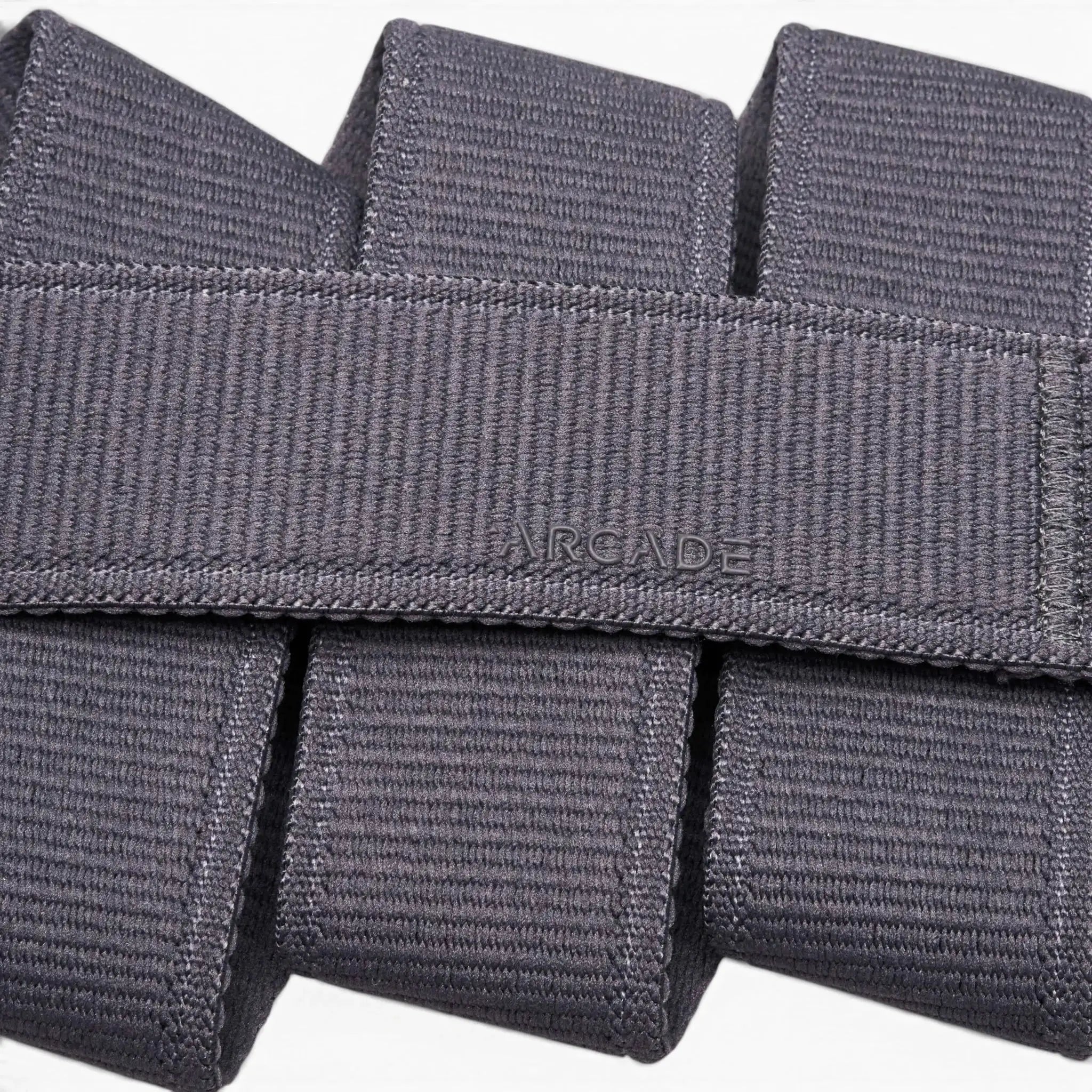 Close-up of the Atlas belt by Arcade Belts, crafted in grey stretch webbing. The word ARCADE is stitched at the center, showcasing its signature woven texture and neatly folded design.