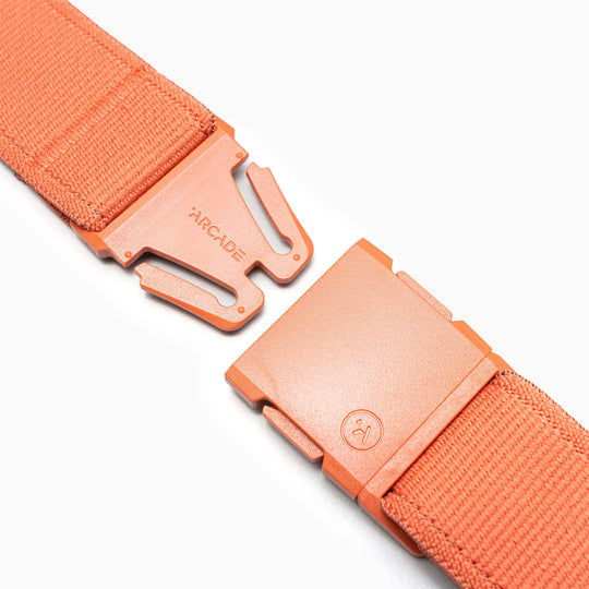 Close-up of the Atlas stretch webbing belt by Arcade Belts, featuring an orange design, low-profile rectangular interlocking buckle, brand name on one side, and a small circular logo on the other.