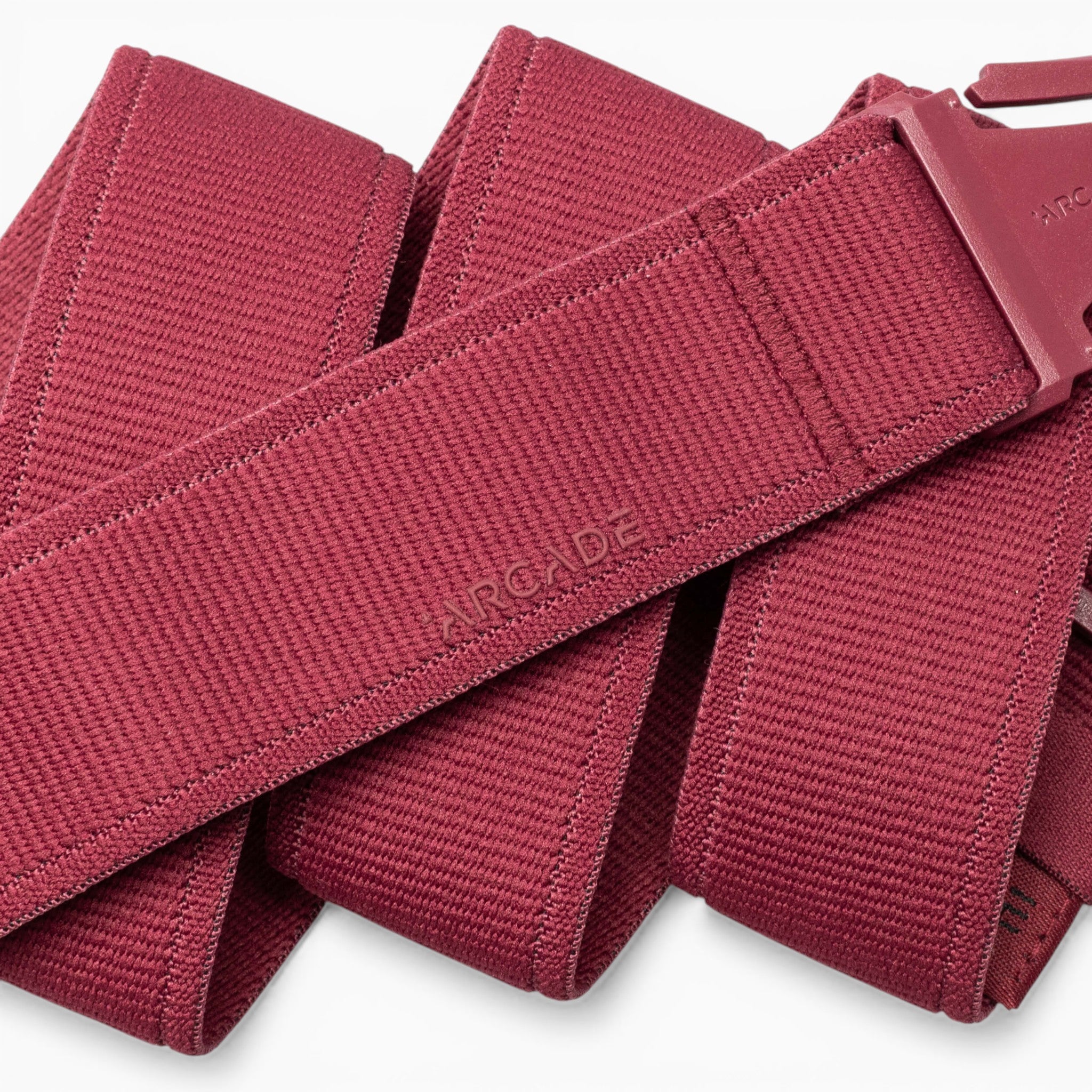 A close-up of the Atlas adventure belt by Arcade Belts, featuring red woven fabric and a matching red A2 buckle, highlighting the textured material and the word “ARCADE” embossed on the belt.