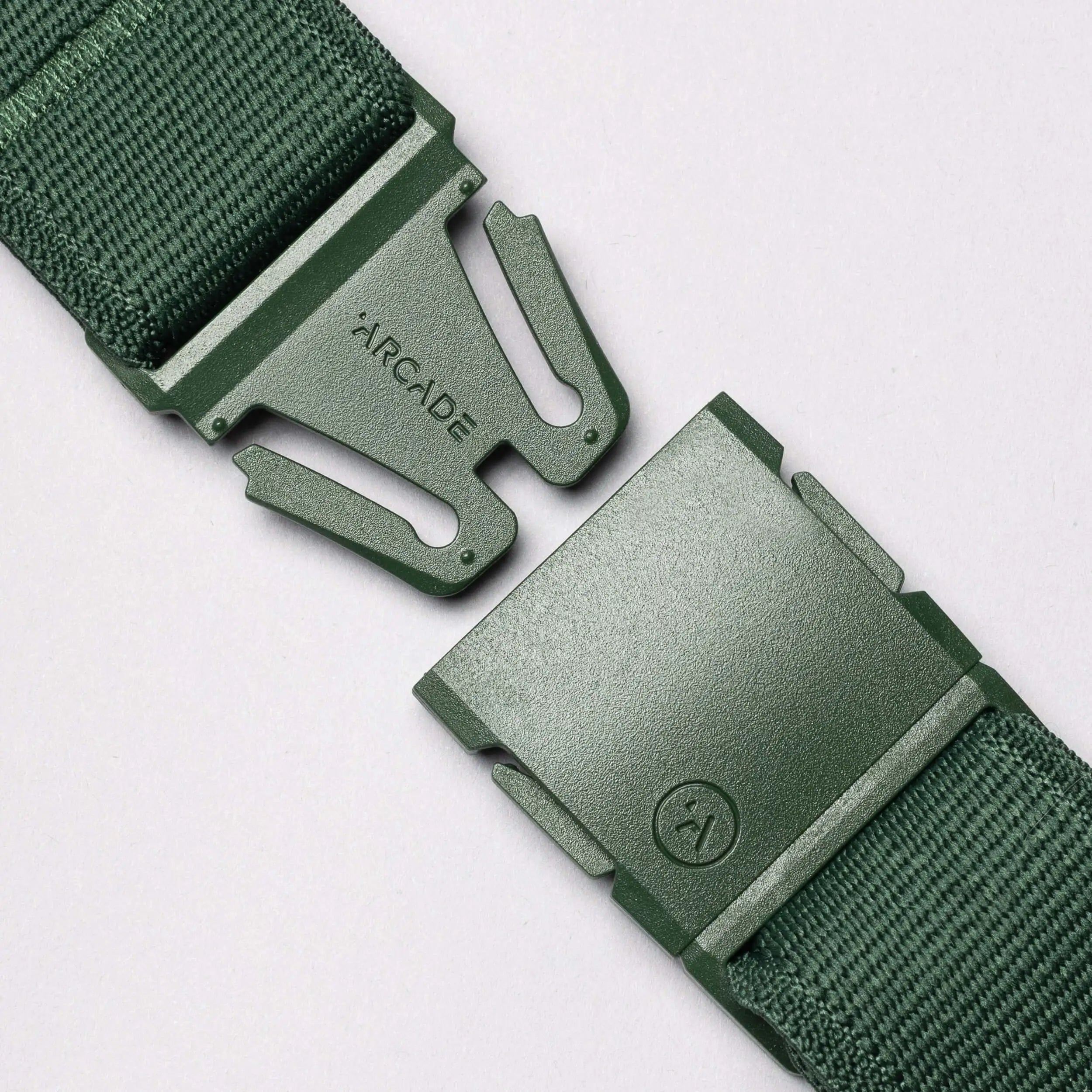 Close-up of the Atlas belt by Arcade Belts in green stretch webbing with a plastic buckle. The separated buckle ends display the ARCADE logo, set against a plain light grey background.