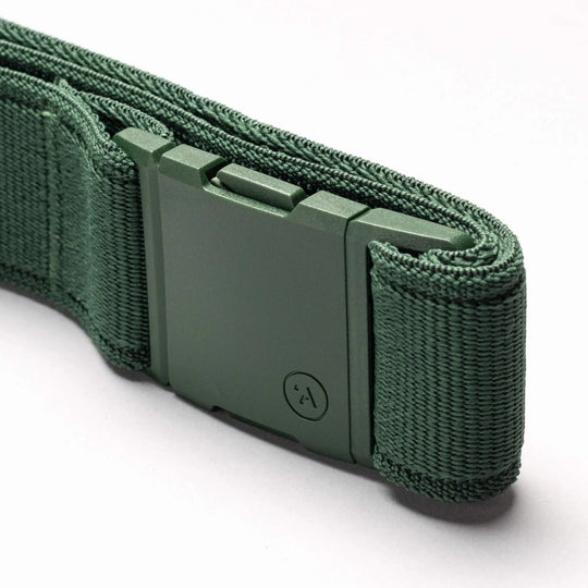 A close-up of the Atlas Elastic Stretch Belt by Arcade Belts in green, featuring a textured woven look and a low-profile rectangular buckle with a small circular symbol, displayed on a light background.