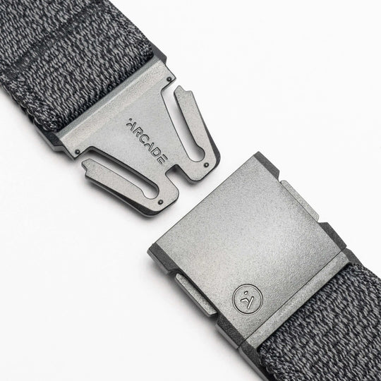 Close-up of the gray Atlas woven elastic stretch belt by Arcade Belts, featuring a metal clasp buckle. The partially open buckle shows ARCADE and a small logo on the metal against a white background.