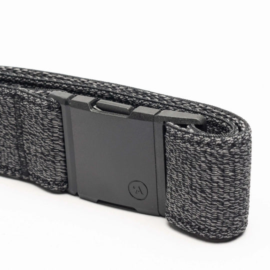 A close-up of the Atlas belt by Arcade Belts, showing its black elastic stretch design with a matte black rectangular buckle and a textured woven pattern with lighter gray threads, neatly folded on a white background.
