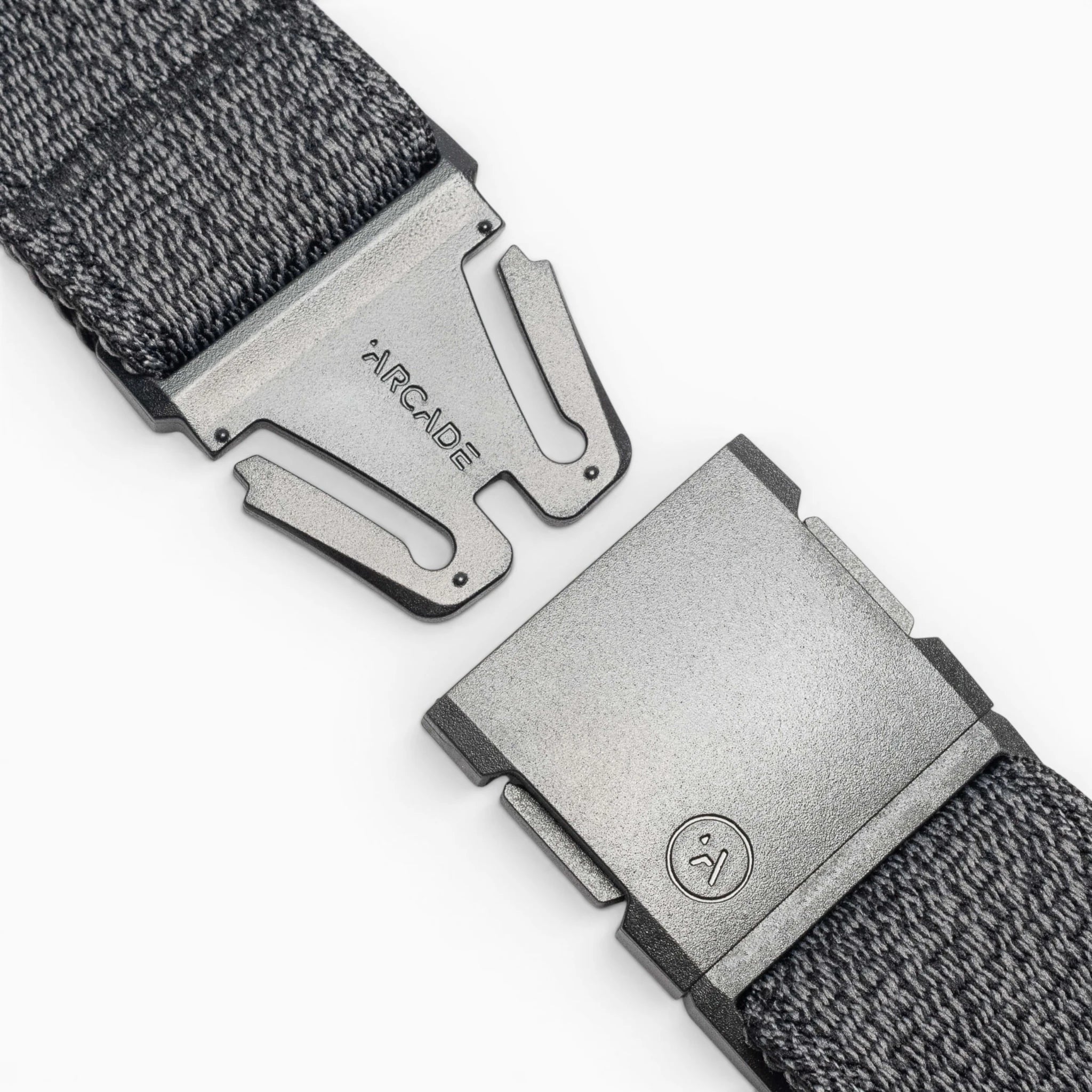 Close-up of the gray Atlas woven elastic stretch belt by Arcade Belts, featuring a metal clasp buckle. The partially open buckle shows ARCADE and a small logo on the metal against a white background.
