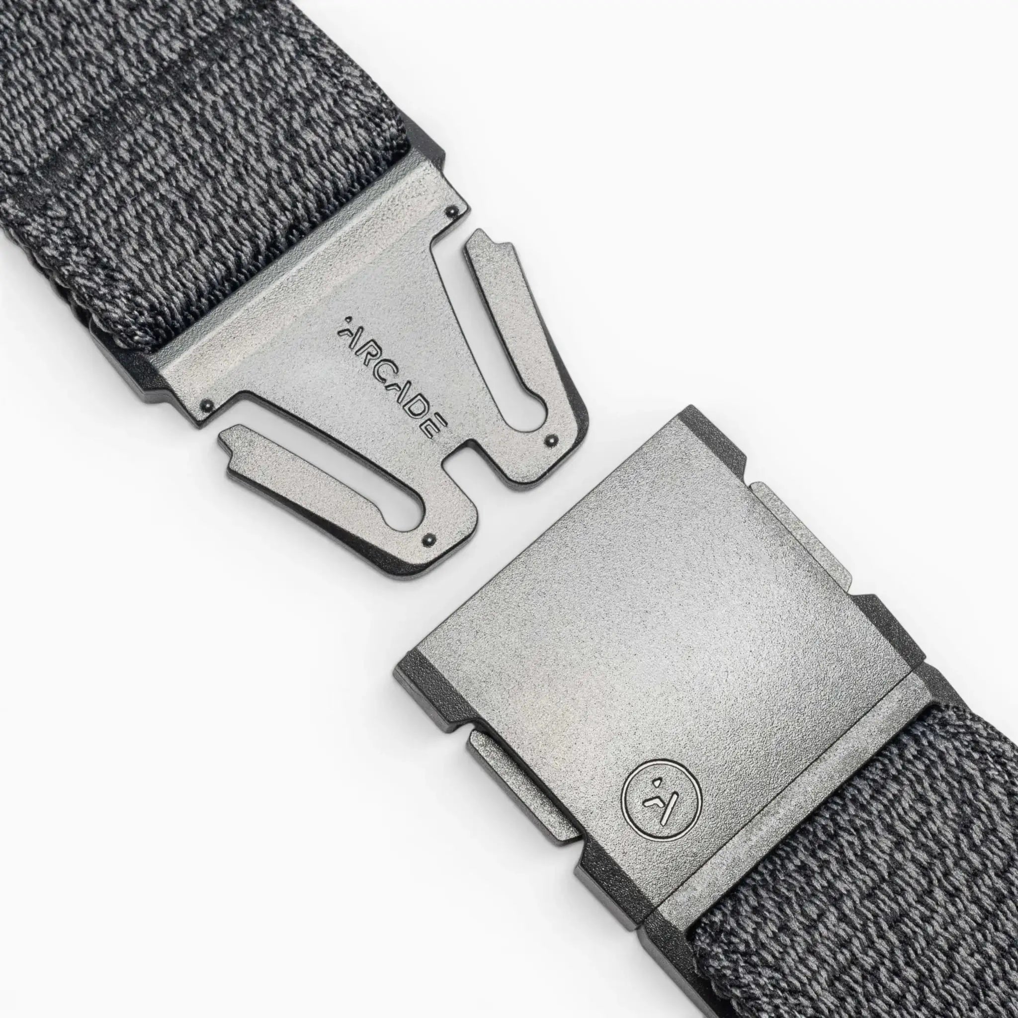 Close-up of the gray Atlas woven elastic stretch belt by Arcade Belts, featuring a metal clasp buckle. The partially open buckle shows ARCADE and a small logo on the metal against a white background.