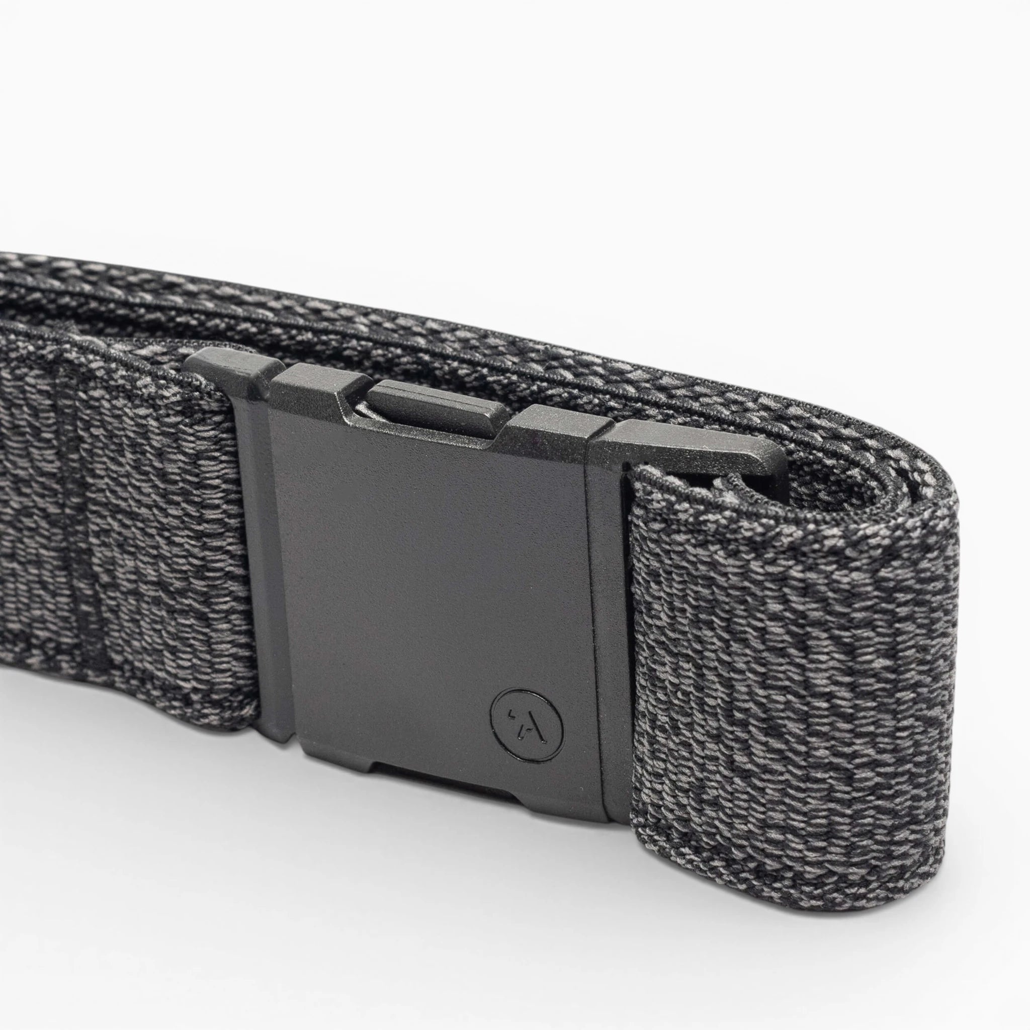 A close-up of the Atlas belt by Arcade Belts, showing its black elastic stretch design with a matte black rectangular buckle and a textured woven pattern with lighter gray threads, neatly folded on a white background.