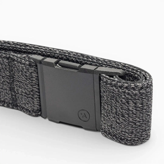 A close-up of the Atlas belt by Arcade Belts, showing its black elastic stretch design with a matte black rectangular buckle and a textured woven pattern with lighter gray threads, neatly folded on a white background.