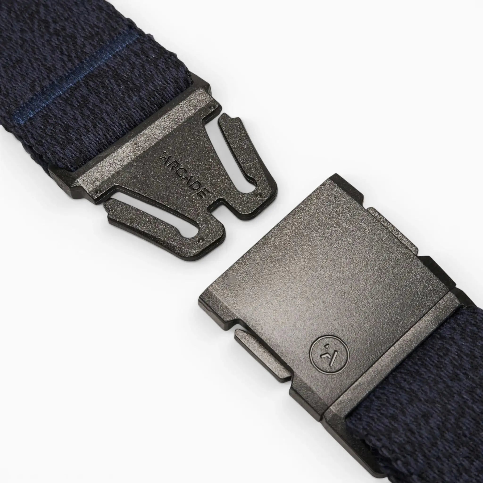 Close-up of a black metal buckle on the navy blue Atlas belt by Arcade Belts, partially unclasped with ARCADE engraved on the clasp, displayed against a plain white background.