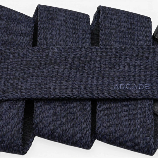 A close-up of a dark blue, textured Atlas belt by Arcade Belts with the brand name subtly printed in small, light blue letters on the surface.