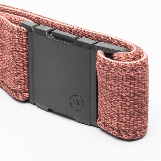 A close-up of the Atlas belt by Arcade Belts, featuring pink stretch woven fabric and a rectangular black buckle, shown against a white background.