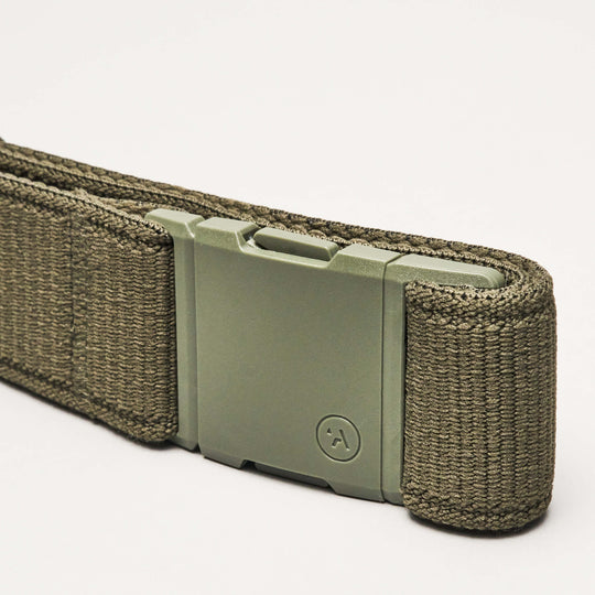 A close-up of the olive green Atlas Low Profile Belt by Arcade Belts, featuring a sturdy rectangular metal buckle and durable woven material, set against a plain white background.