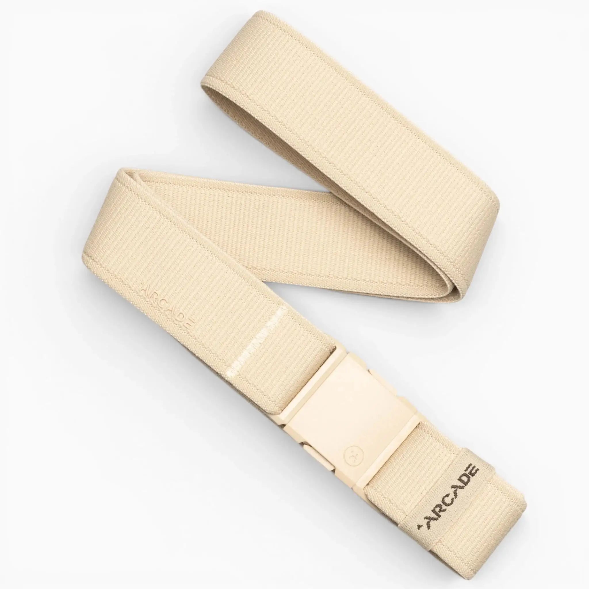 An Atlas belt by Arcade Belts in beige, featuring an adjustable elastic stretch design and a plastic buckle, with Arcade branded near the end. The belt is laid out in a loose zigzag on a white background.
