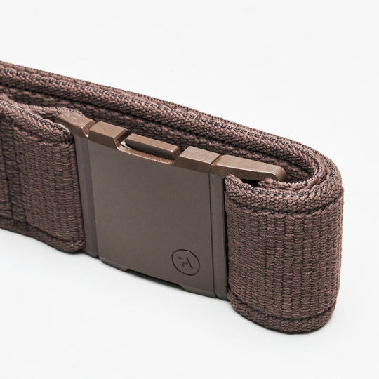 A close-up of the Atlas belt by Arcade Belts, featuring a brown woven elastic stretch design, low-profile style, and a rectangular matte-finish metal buckle, shown against a white background.