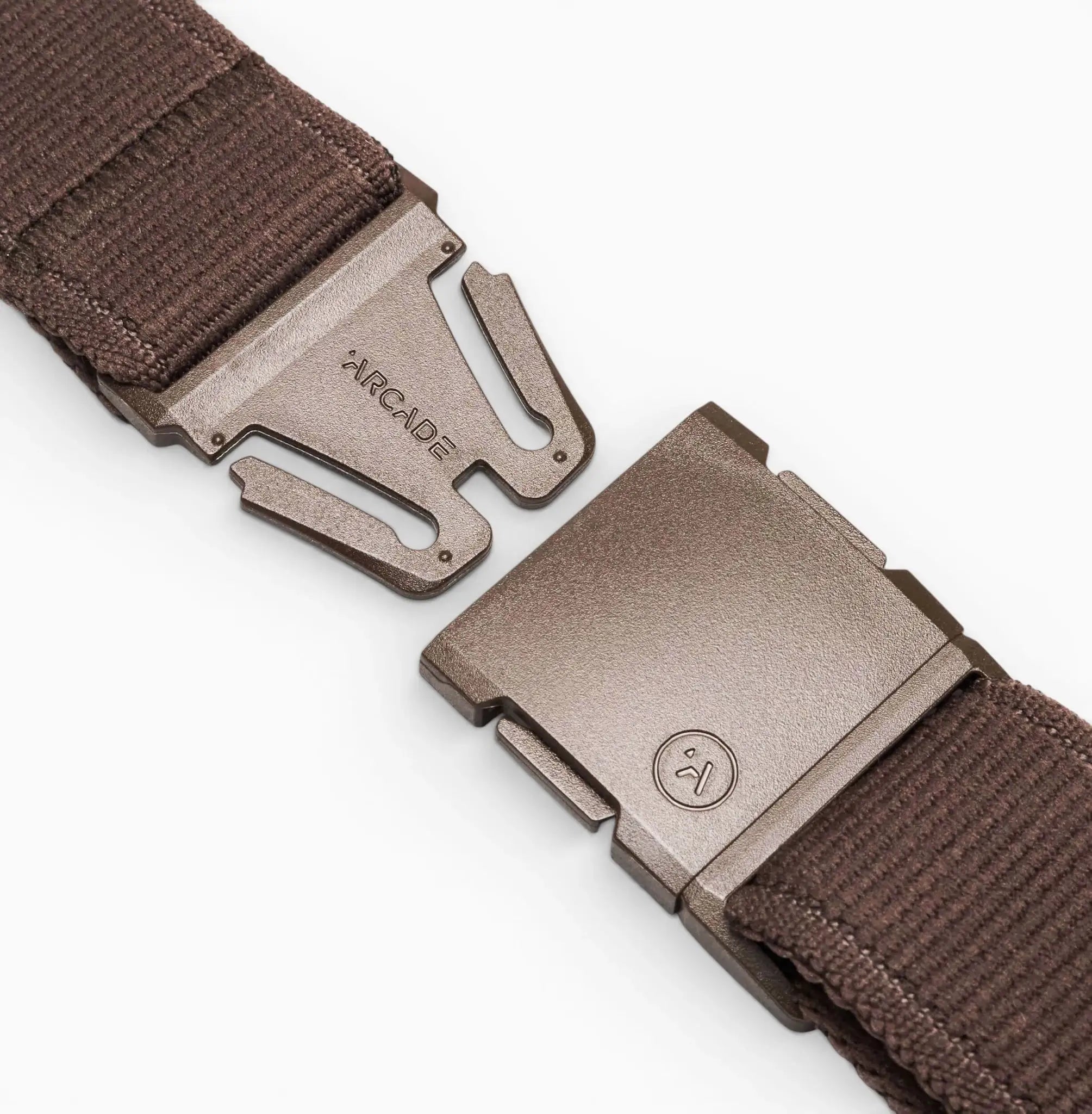 Close-up of the brown Atlas belt by Arcade Belts, crafted from stretch webbing. The open metallic buckle displays two pieces—one engraved with ARCADE and the other featuring a small smiling face logo.