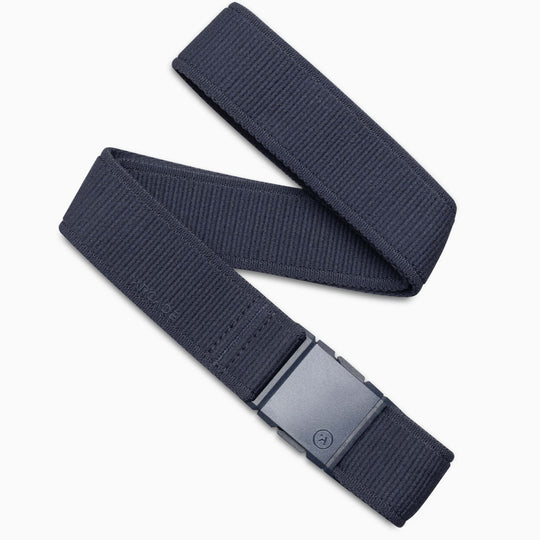 The Atlas by Arcade Belts is a navy blue low-profile belt with a rectangular plastic buckle, shown flat and partially folded on a white background—ideal for travel and daily wear.
