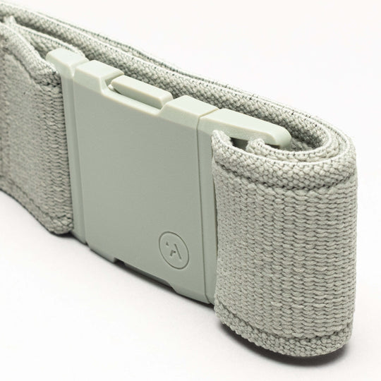 A close-up of the Atlas by Arcade Belts—a light gray, performance stretch strap with an A2 buckle and textured woven material—coiled neatly on a light background, perfect for adventure belt enthusiasts.