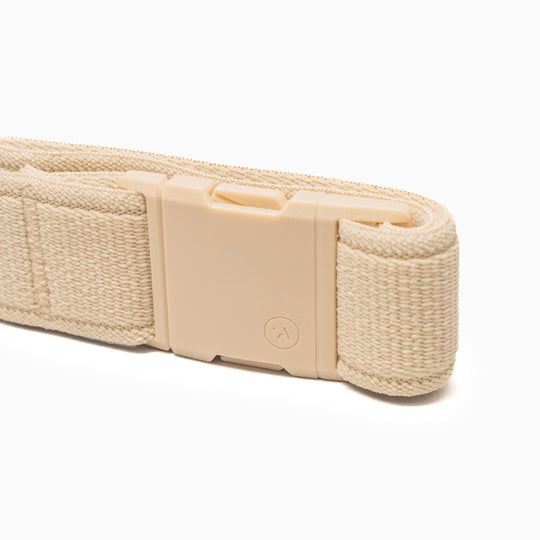 A close-up of the beige Atlas belt by Arcade Belts, featuring stretch woven fabric and a rectangular plastic buckle, shown on a white background.