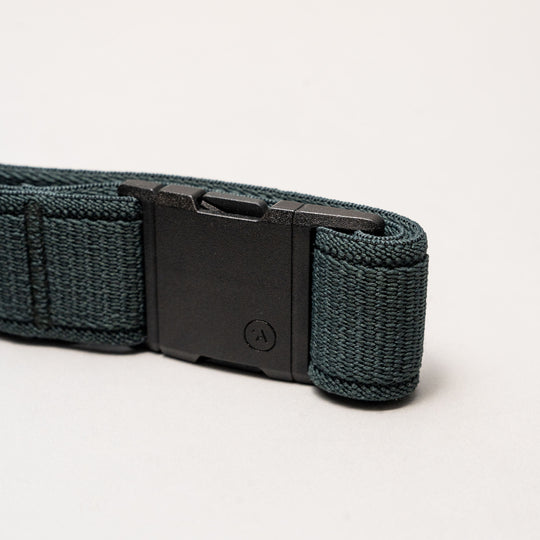 A close-up of an Atlas belt by Arcade Belts features a dark green woven strap and a black plastic buckle, displayed on a light gray background.
