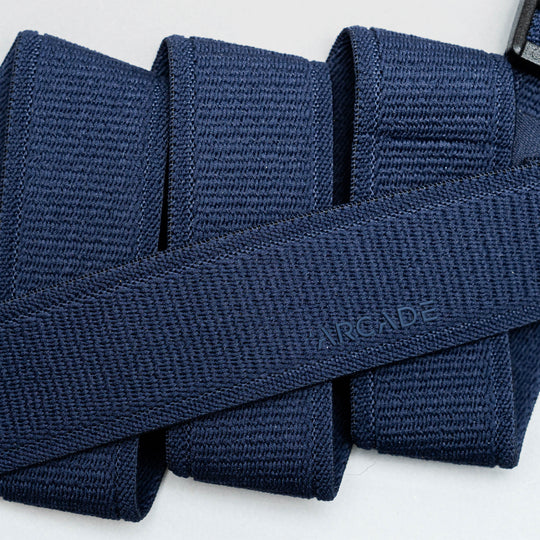 A close-up of the Atlas belt by Arcade Belts in navy blue woven fabric, neatly folded with ARCADE subtly embossed, highlights its Elastic Stretch Belt design for superior comfort and flexibility.