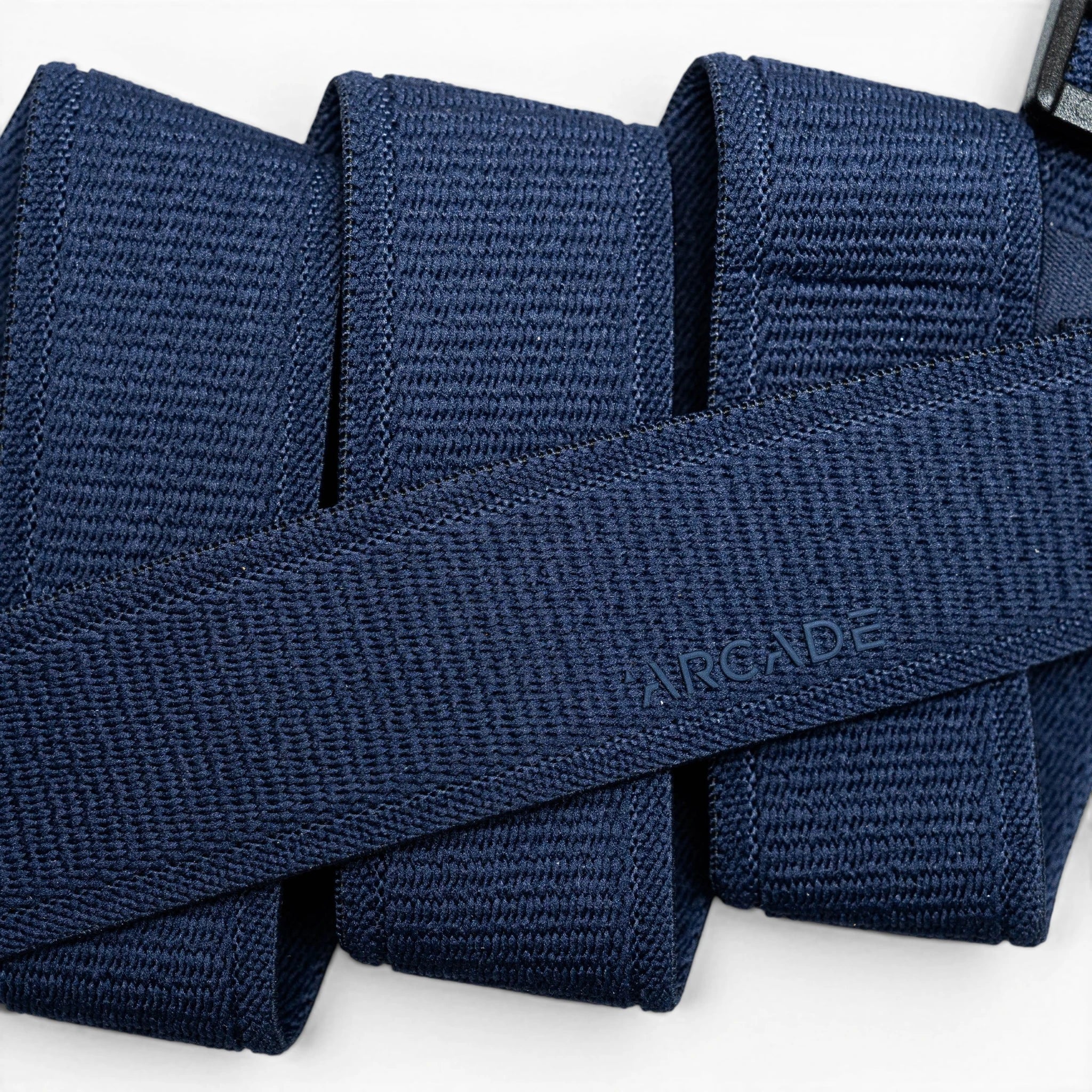 A close-up of the Atlas belt by Arcade Belts in navy blue woven fabric, neatly folded with ARCADE subtly embossed, highlights its Elastic Stretch Belt design for superior comfort and flexibility.