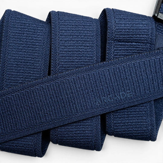 A close-up of the Atlas belt by Arcade Belts in navy blue woven fabric, neatly folded with ARCADE subtly embossed, highlights its Elastic Stretch Belt design for superior comfort and flexibility.