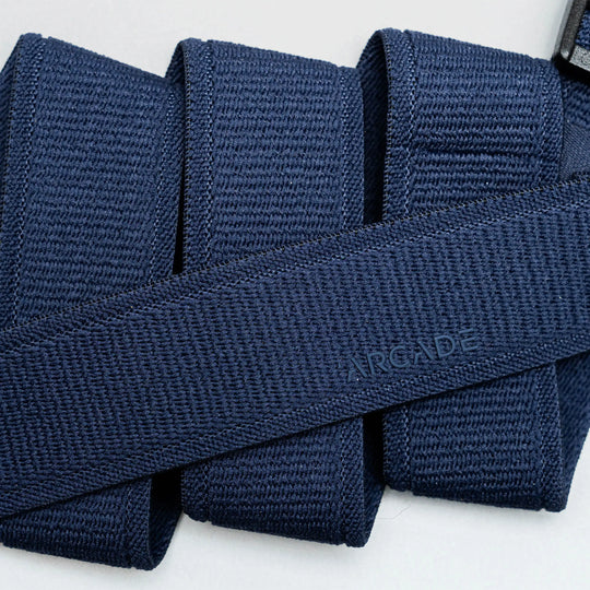 A close-up of the Atlas belt by Arcade Belts in navy blue woven fabric, neatly folded with ARCADE subtly embossed, highlights its Elastic Stretch Belt design for superior comfort and flexibility.