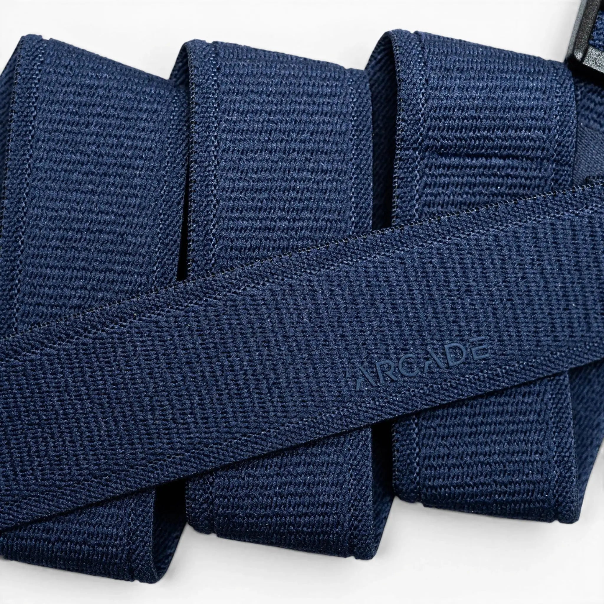 A close-up of the Atlas belt by Arcade Belts in navy blue woven fabric, neatly folded with ARCADE subtly embossed, highlights its Elastic Stretch Belt design for superior comfort and flexibility.