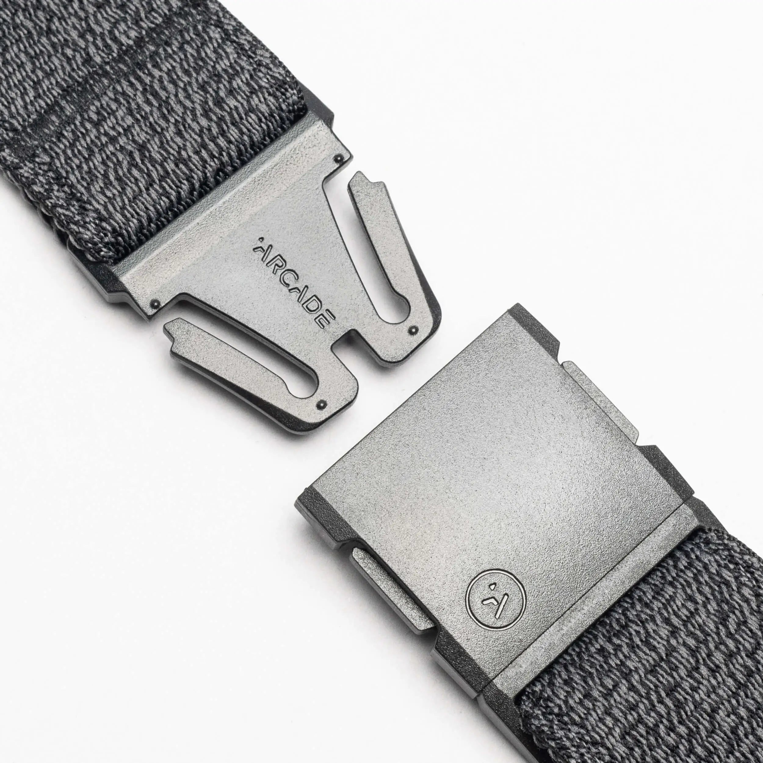 Close-up of the Atlas belt by Arcade Belts in dark gray, featuring a matte plastic buckle with Arcade engraved on one side and a small logo on the other, shown against a white background.
