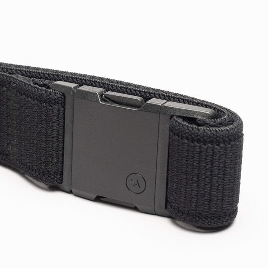 The Atlas by Arcade Belts is a black woven low-profile belt with a matte black rectangular buckle, neatly coiled on a white background—ideal for travel and daily wear.