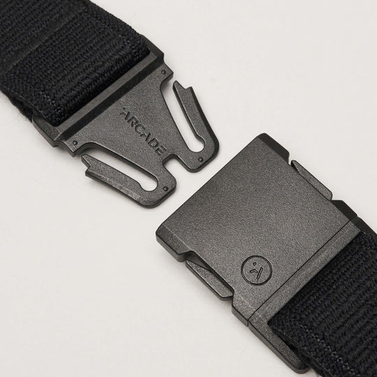 Close-up of the Atlas by Arcade Belts, featuring black stretch webbing and an unfastened plastic interlocking buckle with ARCADE branding—ideal for travel belt enthusiasts.