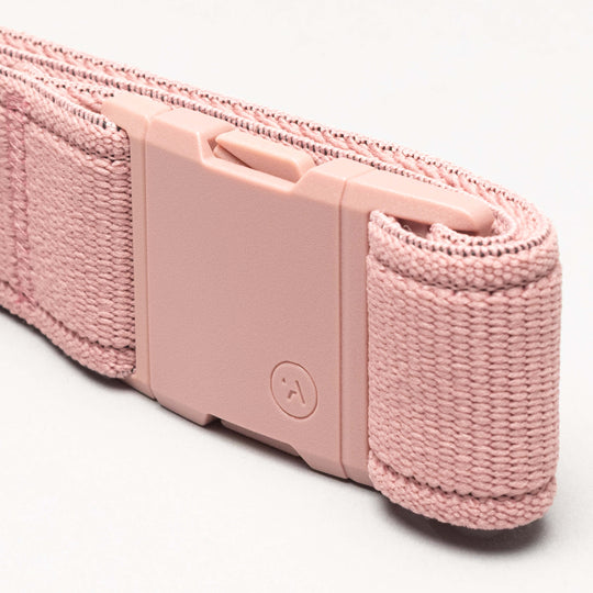 A close-up of the Atlas adventure belt by Arcade Belts, featuring a pink woven strap and matching pink rectangular plastic A2 buckle, neatly rolled on a light background.